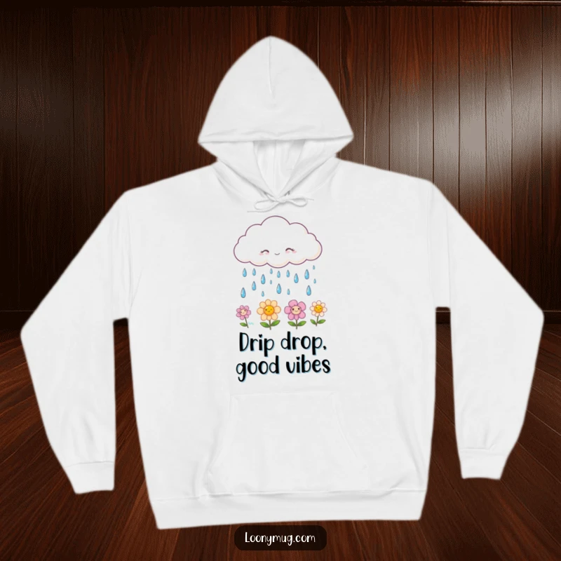Funny hoodie showcasing a fluffy cloud raining smiling raindrops onto blooming happy flowers, offering comfort and a cheerful aesthetic.