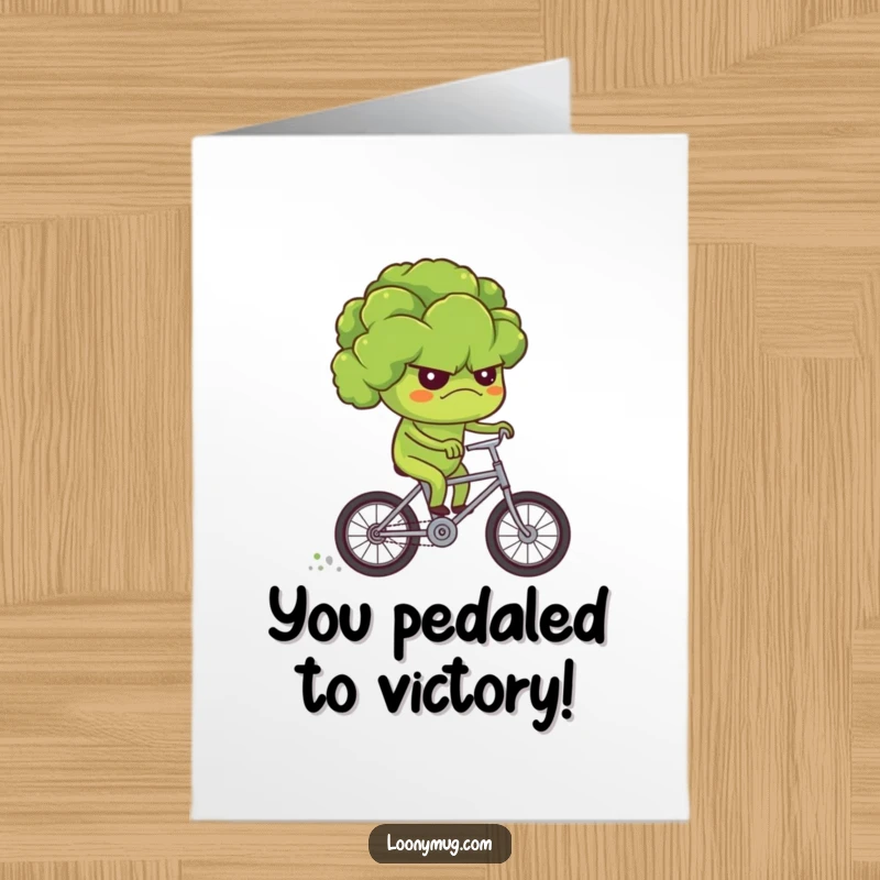 Funny free printable congratulations card: a grumpy broccoli determinedly riding a tiny bicycle, conquering challenges with a frown.
